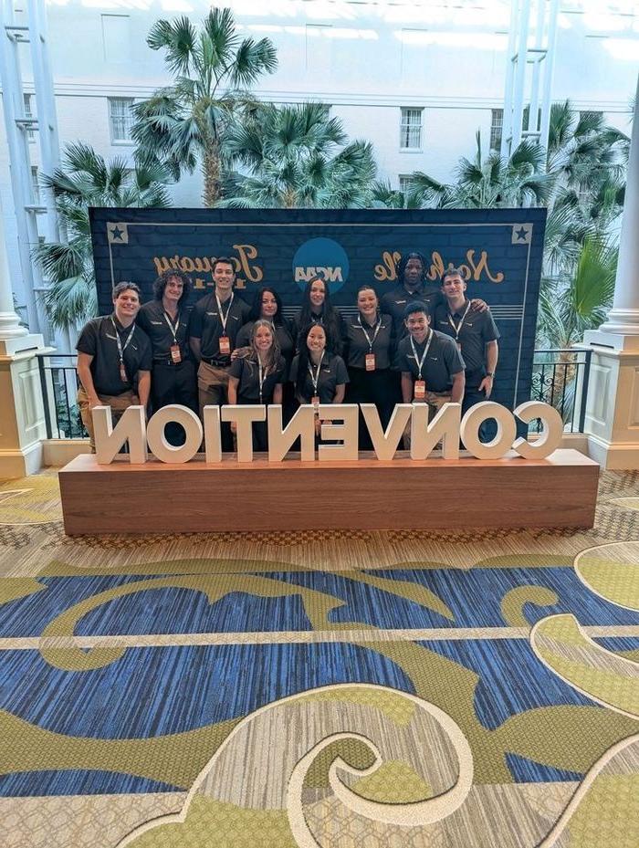 students posing for photo behind "Convention" sign